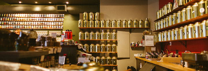 Inside of a Boutique tea shop in Calgary.  Lots of golden tins of tea on racks and shelves. | Naked Leaf